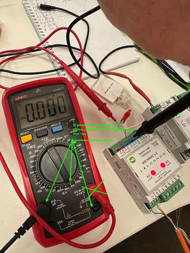 На изображении показан мультиметр с отображением нуля, подключенный к устройству с видимыми проводами и ручками. (Captioned by AI)