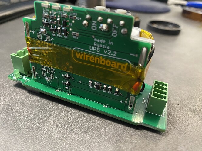 На изображении показана печатная плата с надписью "wirenboard UPS v2.2", на которой присутствуют различные элементы и соединения. (Captioned by AI)