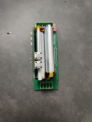 На изображении показана электронная плата с двумя аккумуляторами и кнопками. (Captioned by AI)