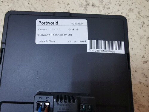 На изображении видна задняя панель устройства с маркировкой Portworld, указанием параметров питания и информацией о производителе Sunworld Technology Ltd. (Captioned by AI)