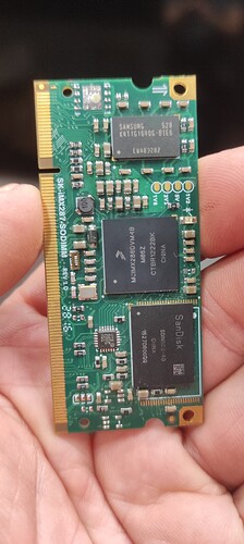 На изображении видно зеленую печатную плату с несколькими микросхемами, которую держат в руке. (Captioned by AI)