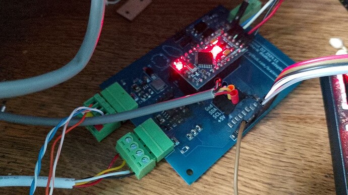 На изображении находится микроконтроллер с красными светодиодами, подключенный к печатной плате с несколькими проводами. (Captioned by AI)