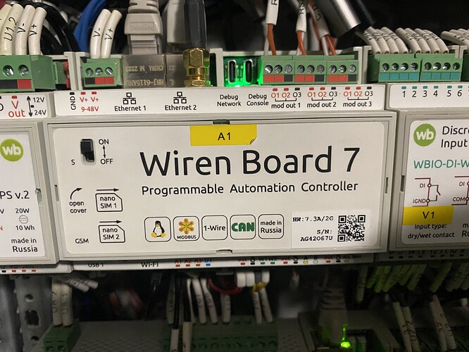 На изображении показан контроллер автоматизации Wiren Board 7, установленный в шкафу управления с подключенными проводами и обозначениями. (Captioned by AI)