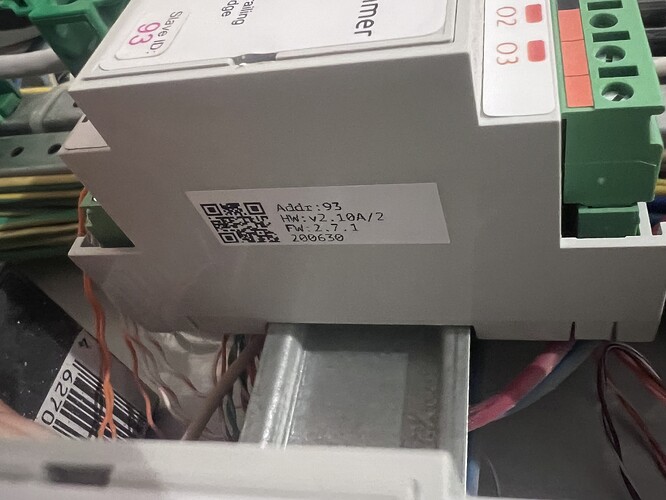 На изображении видно устройство с маркировкой и QR-кодом, находящееся внутри электрического щита. (Captioned by AI)