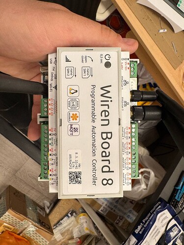 На изображении показан контроллер автоматизации "Wiren Board 8", который удерживается рукой и имеет несколько разъемов и кнопок. (Captioned by AI)