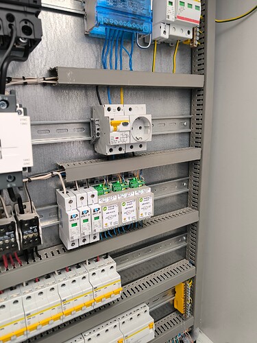 На изображении представлен электрический щит, содержащий переключатели и защитные устройства, установленный на металлическом каркасе. (Captioned by AI)