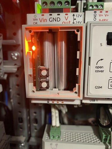 На изображении показан внутренний вид электронного устройства с включенным индикатором в оранжевом цвете и двумя кнопками. (Captioned by AI)