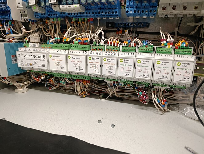 На изображении представлена панель управления с модулями, включая выходы реле, твердотельные реле и дискретные ввода, соединенные проводами. (Captioned by AI)