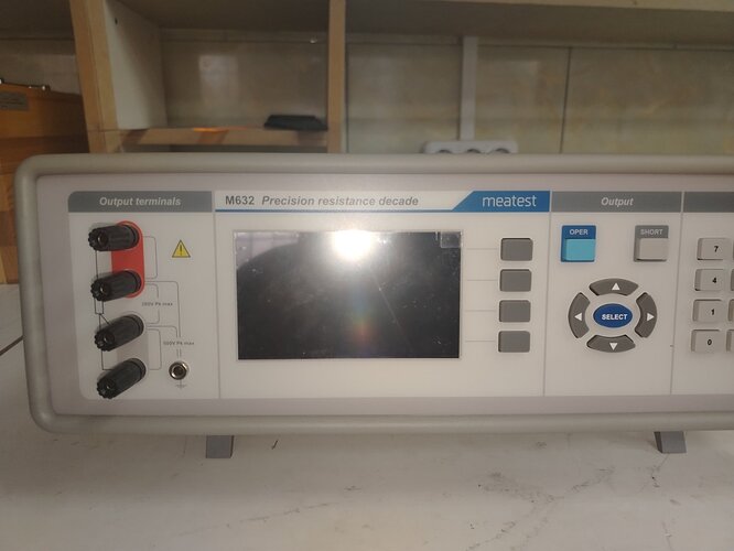 На изображении представлен прибор марки "Meatest" модели М632, предназначенный для измерения и изменения сопротивления с выводами и экраном для отображения данных. (Captioned by AI)