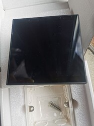 На изображении видно черный экран, помещенный в коробку, с белым поддоном и винтами для крепления. (Captioned by AI)