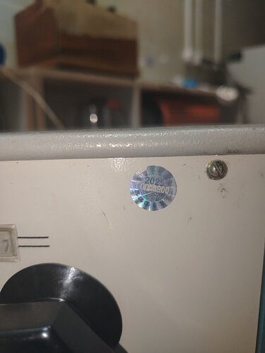 На изображении видно устройство с черной ручкой и голографической наклейкой на светлом корпусе. (Captioned by AI)