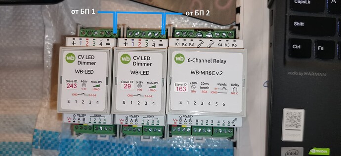 На изображении представлены три модуля управления: два диммера WB-LED и реле WB-MR6C v.2, подключенные к источнику питания с подписанными точками подключения. (Captioned by AI)