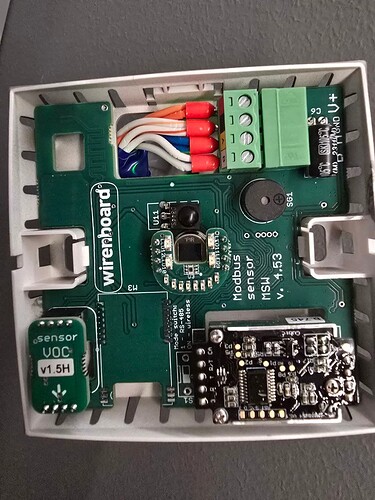 На изображении показана внутренняя часть устройства с платой, на которой расположены различные компоненты, в том числе микросхемы, соединения и сенсоры. (Captioned by AI)