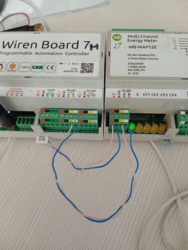 На изображении показаны программируемый контроллер автоматизации Wiren Board 7 и многоканальный счетчик энергии WB-MAP12E, соединенные проводами. (Captioned by AI)