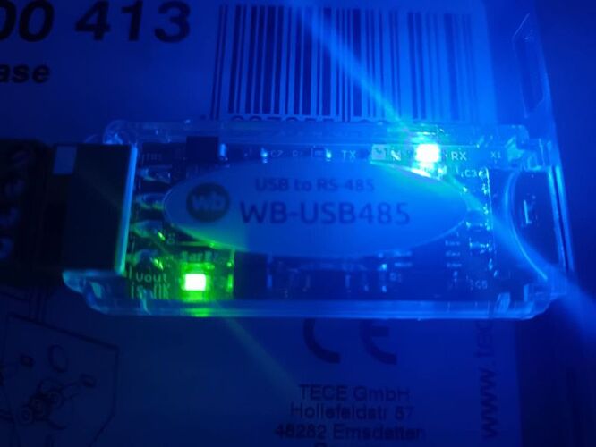 Изображение демонстрирует устройство WB-USB485, конвертер USB в RS-485, со светодиодами, светящимися в темноте. (Captioned by AI)