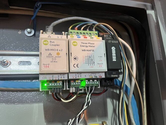 На изображении показаны электрические компоненты, включая Bus Coupler и трехфазный измеритель энергии, установленные в распределительном щите. (Captioned by AI)