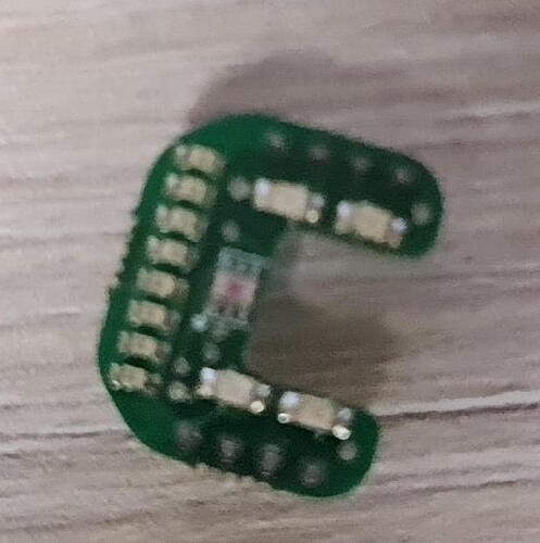 На изображении показана зеленая печатная плата в форме буквы "C" с несколькими контактами. (Captioned by AI)